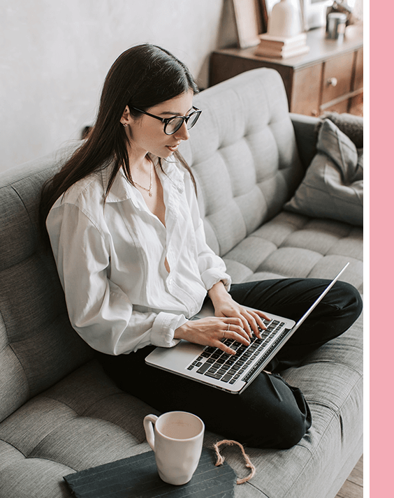 A woman sitting on the couch with her laptop