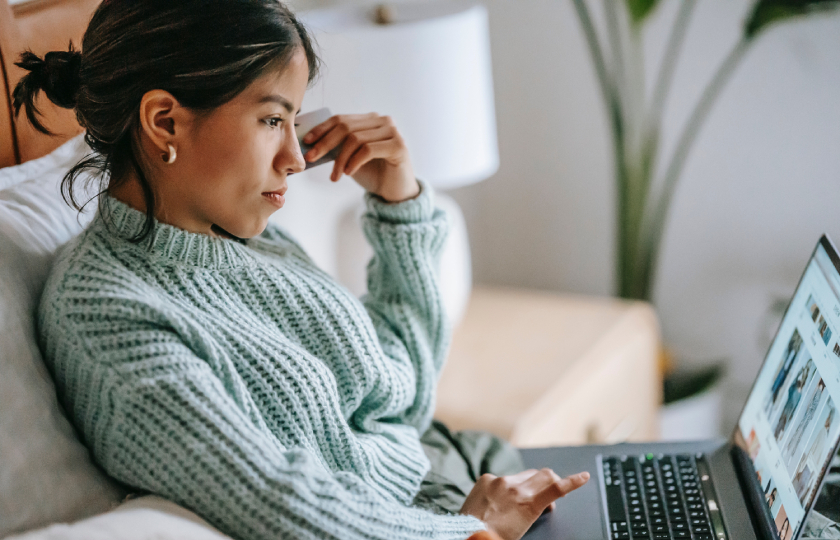 A woman sitting on the couch looking at her laptop.